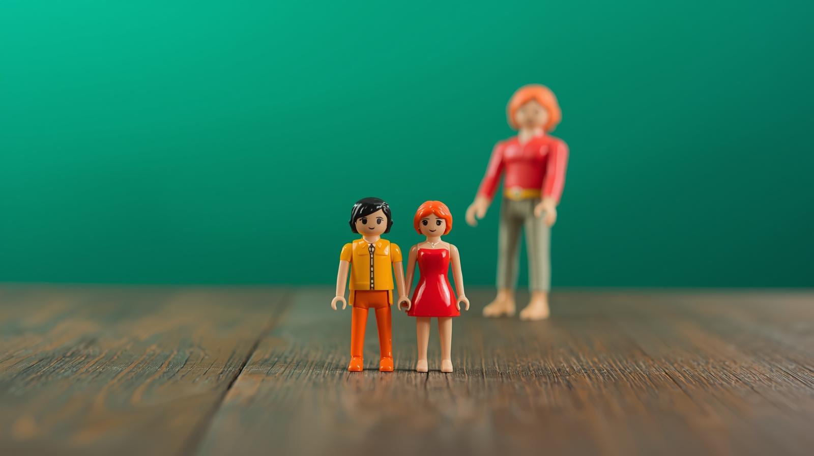 illustration de deux playmobiles regardant vers l'avant, avec en arrière plan, un playmobile plus grand et flou.